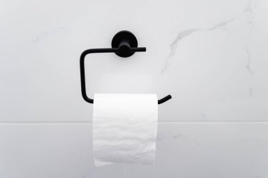 Siyah tuvalet kağıdı tutacağı beyaz mermer döşemeli duvar, ev tadilatı ve banyo veya tuvaletteki iç tasarım ayrıntıları.