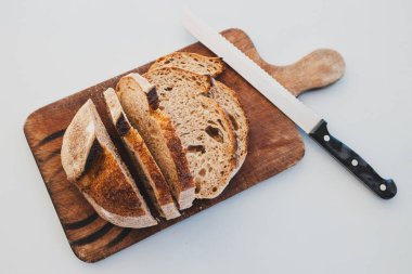 Koyu çavdar ekmeği, sade, sade, saglikli malzemeler kavramını doğrama tahtasıyla dilimlenmiş.