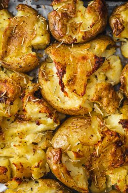 Biberiye, şifalı otlar ve sağlıklı vejetaryen yemek tarifleriyle fırın tepsisinde ezilmiş bebek patatesleri.