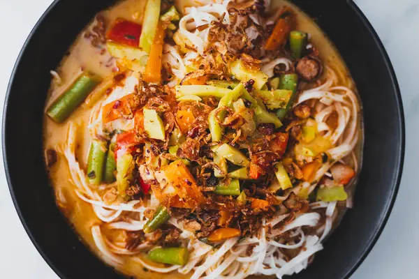 stock image plant-based dan dan rice noodles soup with mixed vegetables and spicy sauce, healthy vegan food recipes