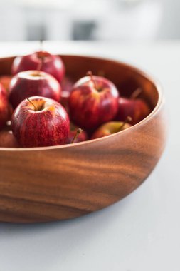 Mutfak tezgahında büyük ahşap meyve kasesinde bir sürü kırmızı elma var. Basit, sağlıklı malzemeler kavramı.