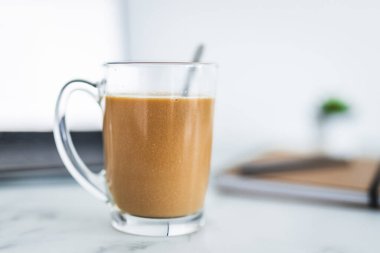 Ev arka planında bulanık bir fincanın önünde kahveyle el ele tutuşmak, alan derinliği, alışkanlıklar ve yaşam tarzı kavramı.