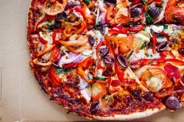 Üstünde soğan zeytinli domates, dolmalık biber, İtalyan yemeği ve paket servis konseptiyle servis kutusunda sebze pizzası.