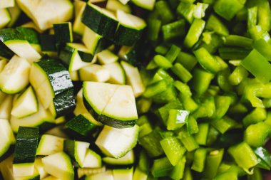 Tahta kesme tahtasının üzerinde doğranmış yeşil dolmalık biber ve kabak. Basit, sağlıklı malzemeler kavramı.