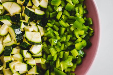 Tahta kesme tahtasının üzerinde doğranmış yeşil dolmalık biber ve kabak. Basit, sağlıklı malzemeler kavramı.
