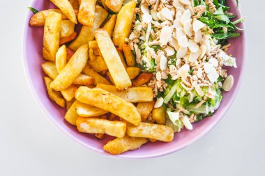 Tofu ve bademle kaplanmış yarım patates kızartması ve yarım salata, sağlıklı yemek abur cubur konseptine karşı sağlıklı ve tatmin edici denge.