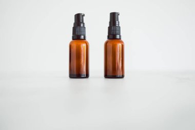 Minimalistik beyaz mermer arka planda eczacı kehribar tarzı şişe ile aynı göz serumu nemlendiricileri. 