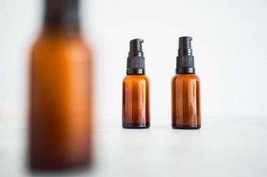 Minimalistik beyaz mermer arka planda eczacı kehribar tarzı şişe ile aynı göz serumu nemlendiricileri. 