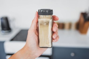 Mutfak tezgahının önünde cam zencefil kavanozu, sıfırdan pişirme kavramı ve organize bir kiler.