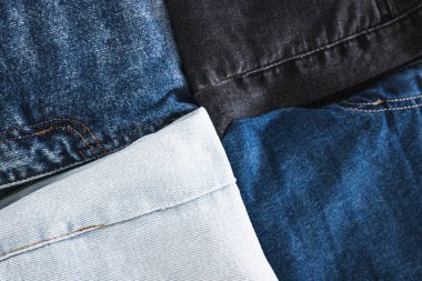 Farklı renk kot kumaşlı kot pantolon yığını düzgünce katlandı ve minimalist arka planda yığıldı