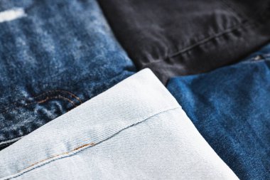 Farklı renk kot kumaşlı kot pantolon yığını düzgünce katlandı ve minimalist arka planda yığıldı