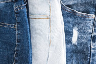 Farklı renk kot kumaşlı kot pantolon yığını düzgünce katlandı ve minimalist arka planda yığıldı