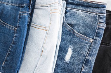 Farklı renk kot kumaşlı kot pantolon yığını düzgünce katlandı ve minimalist arka planda yığıldı