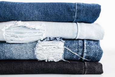 Farklı renk kot kumaşlı kot pantolon yığını düzgünce katlandı ve minimalist arka planda yığıldı