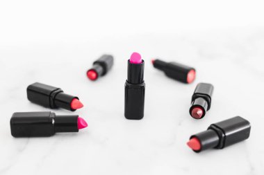 Gösteriş masasına saçılmış renkli ruj grupları, minimalist zarif mermer arka plan, aşırı sığ alan derinliği