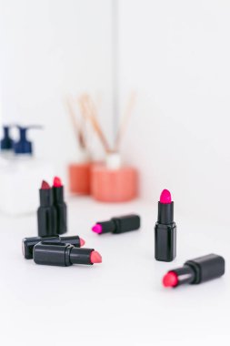 Gösteriş masasına saçılmış renkli ruj grupları, minimalist zarif mermer arka plan, aşırı sığ alan derinliği