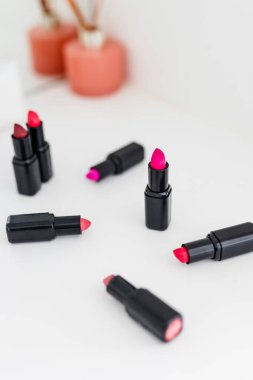 Gösteriş masasına saçılmış renkli ruj grupları, minimalist zarif mermer arka plan, aşırı sığ alan derinliği