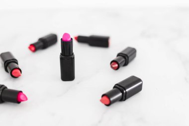 Gösteriş masasına saçılmış renkli ruj grupları, minimalist zarif mermer arka plan, aşırı sığ alan derinliği