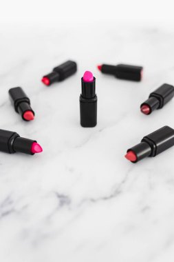 Gösteriş masasına saçılmış renkli ruj grupları, minimalist zarif mermer arka plan, aşırı sığ alan derinliği