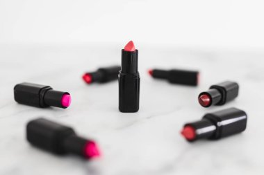 Gösteriş masasına saçılmış renkli ruj grupları, minimalist zarif mermer arka plan, aşırı sığ alan derinliği