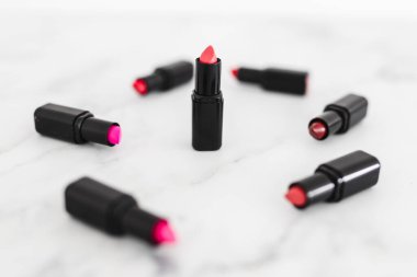 Gösteriş masasına saçılmış renkli ruj grupları, minimalist zarif mermer arka plan, aşırı sığ alan derinliği