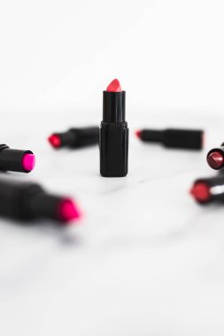 Gösteriş masasına saçılmış renkli ruj grupları, minimalist zarif mermer arka plan, aşırı sığ alan derinliği