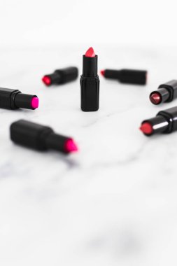 Gösteriş masasına saçılmış renkli ruj grupları, minimalist zarif mermer arka plan, aşırı sığ alan derinliği