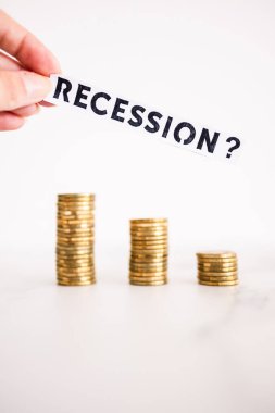 Tasarruf ve kazancın azaltılması sembolü olan bozuk para yığınları önünde soru işareti içeren durgunluk metni
