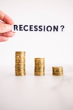 Tasarruf ve kazancın azaltılması sembolü olan bozuk para yığınları önünde soru işareti içeren durgunluk metni