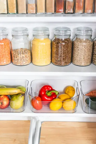 Taneciklerle, baklagillerle, baharatlarla ve konteynırlarda taze ürünlerle dolu, sağlıklı beslenme, düzenli ev, organizasyon ve düşüşle dolu küçük, düzenli bir kiler.