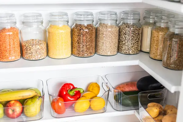 Taneciklerle, baklagillerle, baharatlarla ve konteynırlarda taze ürünlerle dolu, sağlıklı beslenme, düzenli ev, organizasyon ve düşüşle dolu küçük, düzenli bir kiler.