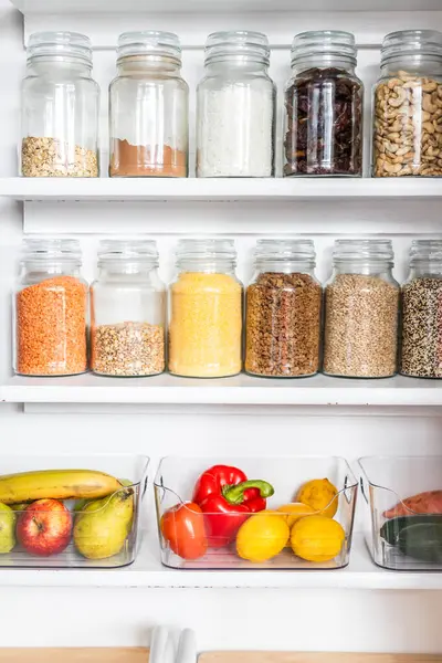 Taneciklerle, baklagillerle, baharatlarla ve konteynırlarda taze ürünlerle dolu, sağlıklı beslenme, düzenli ev, organizasyon ve düşüşle dolu küçük, düzenli bir kiler.