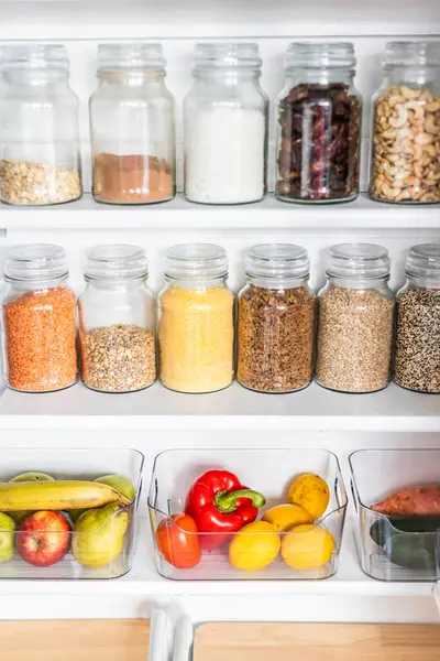 Taneciklerle, baklagillerle, baharatlarla ve konteynırlarda taze ürünlerle dolu, sağlıklı beslenme, düzenli ev, organizasyon ve düşüşle dolu küçük, düzenli bir kiler.