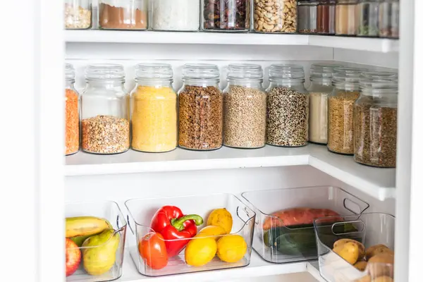Taneciklerle, baklagillerle, baharatlarla ve konteynırlarda taze ürünlerle dolu, sağlıklı beslenme, düzenli ev, organizasyon ve düşüşle dolu küçük, düzenli bir kiler.