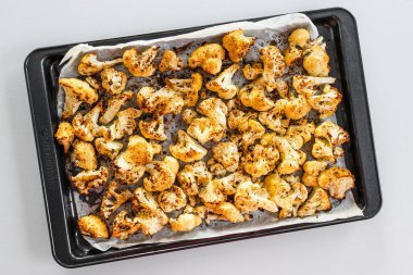 Kızardıktan sonra büyük bir tepside baharatlı taze karnabahar, ev yemeği ve yemek hazırlığı.