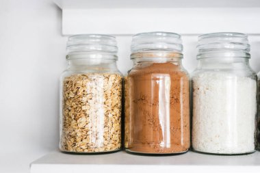 Temiz kiler, yulaf ezmeli kavanozlar ve düzenli organize edilmiş estetik kiler rafı, gıda deposu ve güzel organize ev konsepti içindeki tatlı malzemeler.