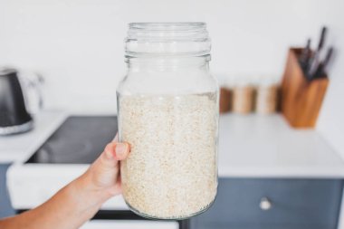 Mutfak tezgahının önünde cam bir kavanoz arborio pilavı, sıfırdan pişirme konsepti ve organize bir kiler.