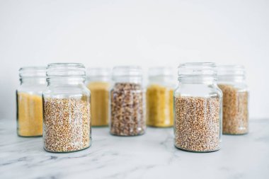 İçinde kinoa pirinç karabuğday kuskusu ve arpa da dahil olmak üzere içinde farklı tahıl türleri bulunan temiz kiler kavanozları, basit doğal sağlıklı bileşenler kavramı.