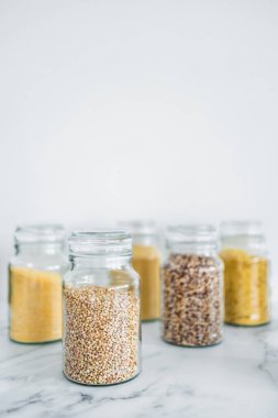 İçinde kinoa pirinç karabuğday kuskusu ve arpa da dahil olmak üzere içinde farklı tahıl türleri bulunan temiz kiler kavanozları, basit doğal sağlıklı bileşenler kavramı.