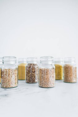 İçinde kinoa pirinç karabuğday kuskusu ve arpa da dahil olmak üzere içinde farklı tahıl türleri bulunan temiz kiler kavanozları, basit doğal sağlıklı bileşenler kavramı.