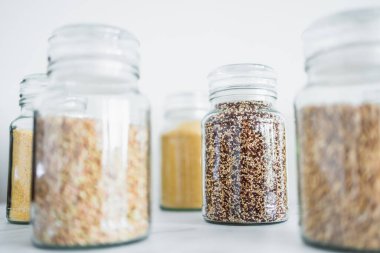 İçinde kinoa pirinç karabuğday kuskusu ve arpa da dahil olmak üzere içinde farklı tahıl türleri bulunan temiz kiler kavanozları, basit doğal sağlıklı bileşenler kavramı.