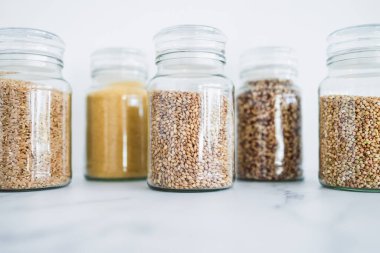 İçinde kinoa pirinç karabuğday kuskusu ve arpa da dahil olmak üzere içinde farklı tahıl türleri bulunan temiz kiler kavanozları, basit doğal sağlıklı bileşenler kavramı.