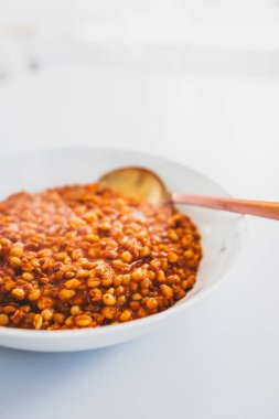 Bol bol pişmiş freekeh, mercimek ve domates sosu, sağlıklı bitkisel tarifler ve temiz yemek temaları.