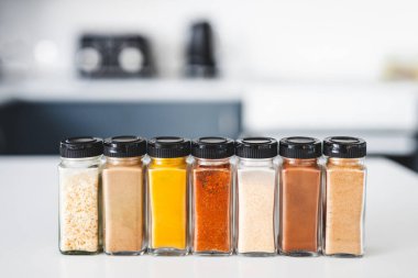 Cam kavanozlar dolusu sarımsak, soğan, zerdeçal, kırmızı biber, zencefil, garam masala ve Çin baharatı mutfak tezgahına dizilmiş, yemek pişirme, yemek hazırlama ve mutfak teması için mükemmel.