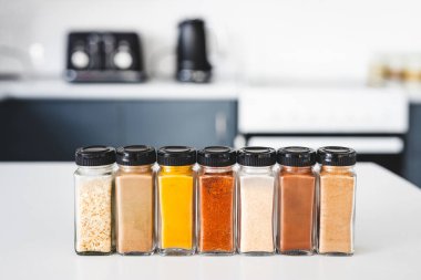 Cam kavanozlar dolusu sarımsak, soğan, zerdeçal, kırmızı biber, zencefil, garam masala ve Çin baharatı mutfak tezgahına dizilmiş, yemek pişirme, yemek hazırlama ve mutfak teması için mükemmel.