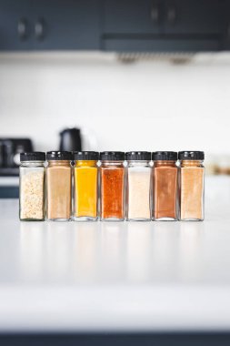 Cam kavanozlar dolusu sarımsak, soğan, zerdeçal, kırmızı biber, zencefil, garam masala ve Çin baharatı mutfak tezgahına dizilmiş, yemek pişirme, yemek hazırlama ve mutfak teması için mükemmel.