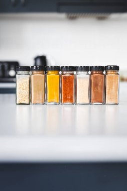 Cam kavanozlar dolusu sarımsak, soğan, zerdeçal, kırmızı biber, zencefil, garam masala ve Çin baharatı mutfak tezgahına dizilmiş, yemek pişirme, yemek hazırlama ve mutfak teması için mükemmel.