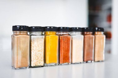 Cam kavanozlar dolusu sarımsak, soğan, zerdeçal, kırmızı biber, zencefil, garam masala ve Çin baharatı mutfak tezgahına dizilmiş, yemek pişirme, yemek hazırlama ve mutfak teması için mükemmel.