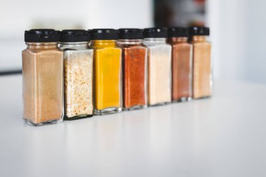 Cam kavanozlar dolusu sarımsak, soğan, zerdeçal, kırmızı biber, zencefil, garam masala ve Çin baharatı mutfak tezgahına dizilmiş, yemek pişirme, yemek hazırlama ve mutfak teması için mükemmel.