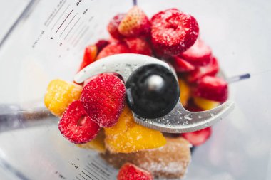 Donmuş çilek, muz ve mango karışımından yapılmış, karıştırılmaya hazır. Sağlıklı yaşam tarzı teması, doğal ışık ile renkli sahne